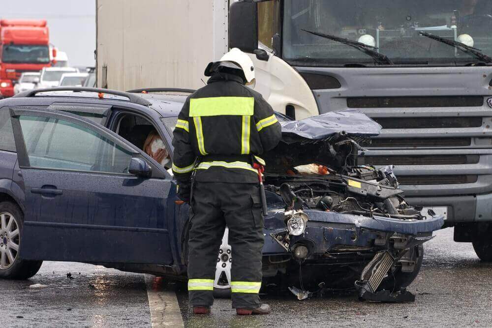 Police officer checking on highway accident between car and truck.