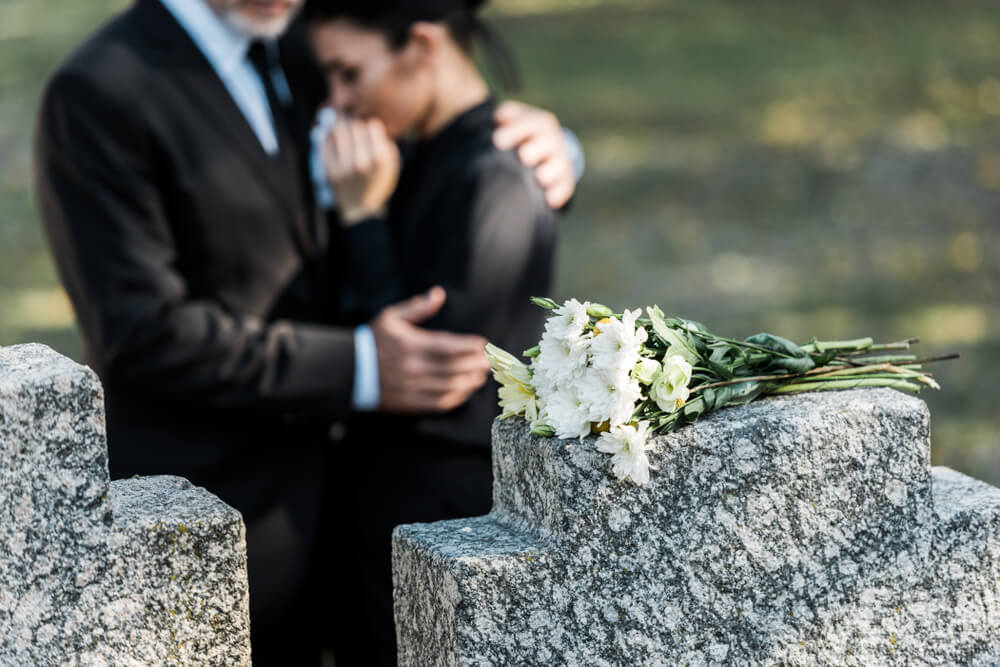 Lady crying in the cemetery over the loss of her father.