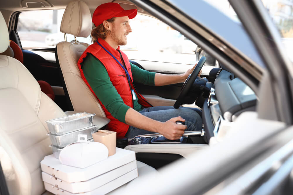 Food delivery driver with orders in car.