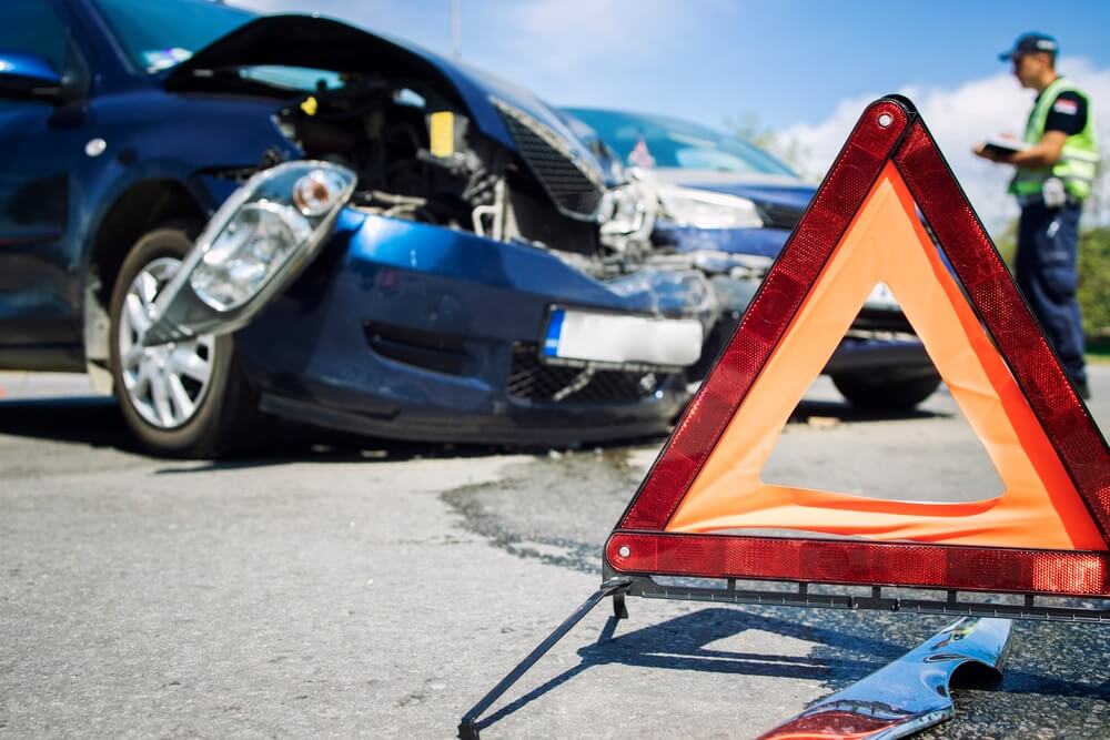 Police officer inspecting car accident in the road.