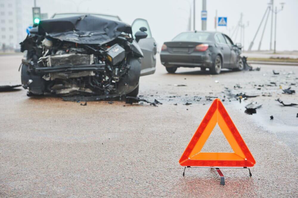 Highway car collision with warning sign on the road.