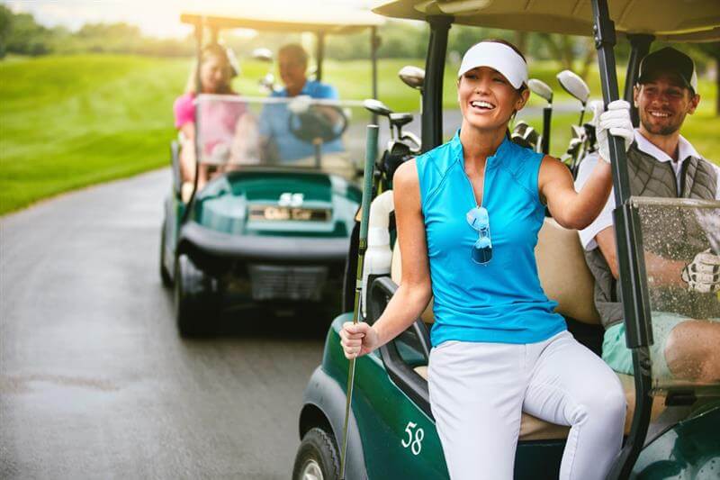 Happy couples riding in the golf cart.