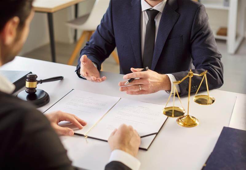 Unrecognizable experienced lawyer gives consultancy to his new client dressed formally shares legal advice explains some details going to sign documents.