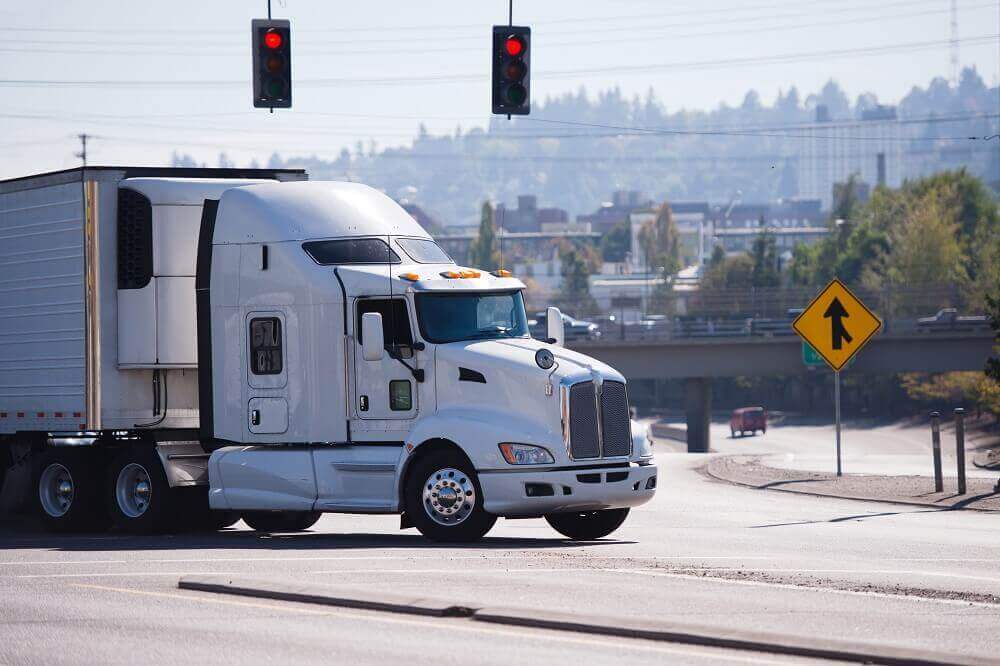 White truck passing traffic lights highway.
