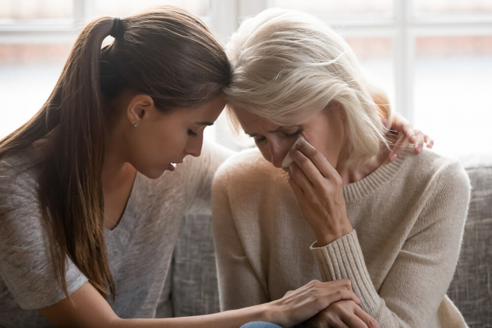 Daughter comforting her mother over loss of her late husband due to accident.